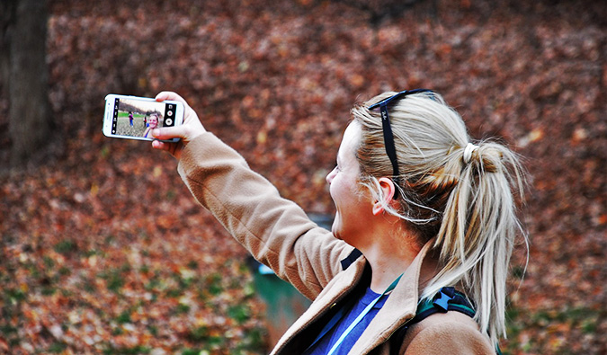 A solo female traveler taking a selfie in the woods on a sunny day