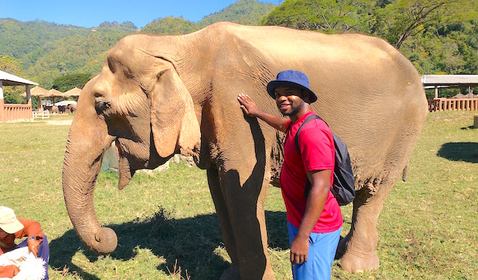 Alex standing near a rescued elephant while traveling in Southeast Asia