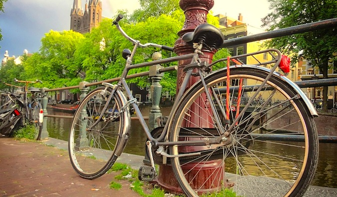 Bike leaning against a post along a canal in Amsterdam