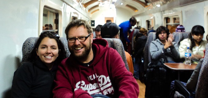 A traveling couple posing for a photo on a busy train