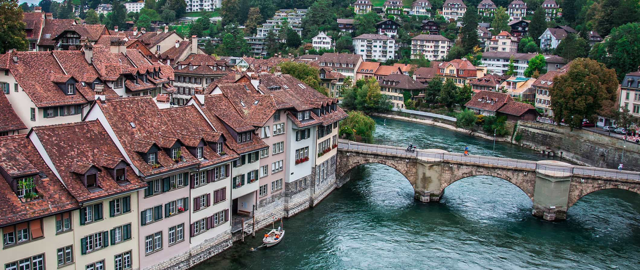 The charming buildings of Bern, Switzerland along the river with hillside houses in the background