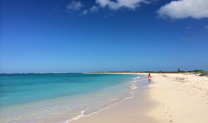 A person walking down the wide, sandy beach on Anegada