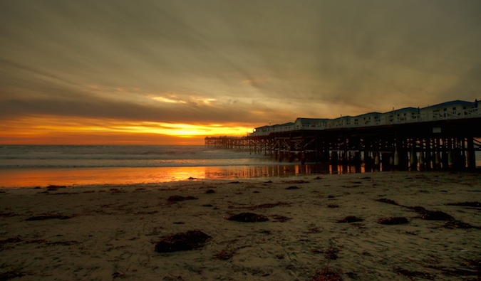 A tall wooden pier on the San Diego beach during sunset