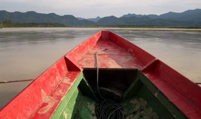 The tip of a red canoe as it floats along in the Bolivian amazon rainforest