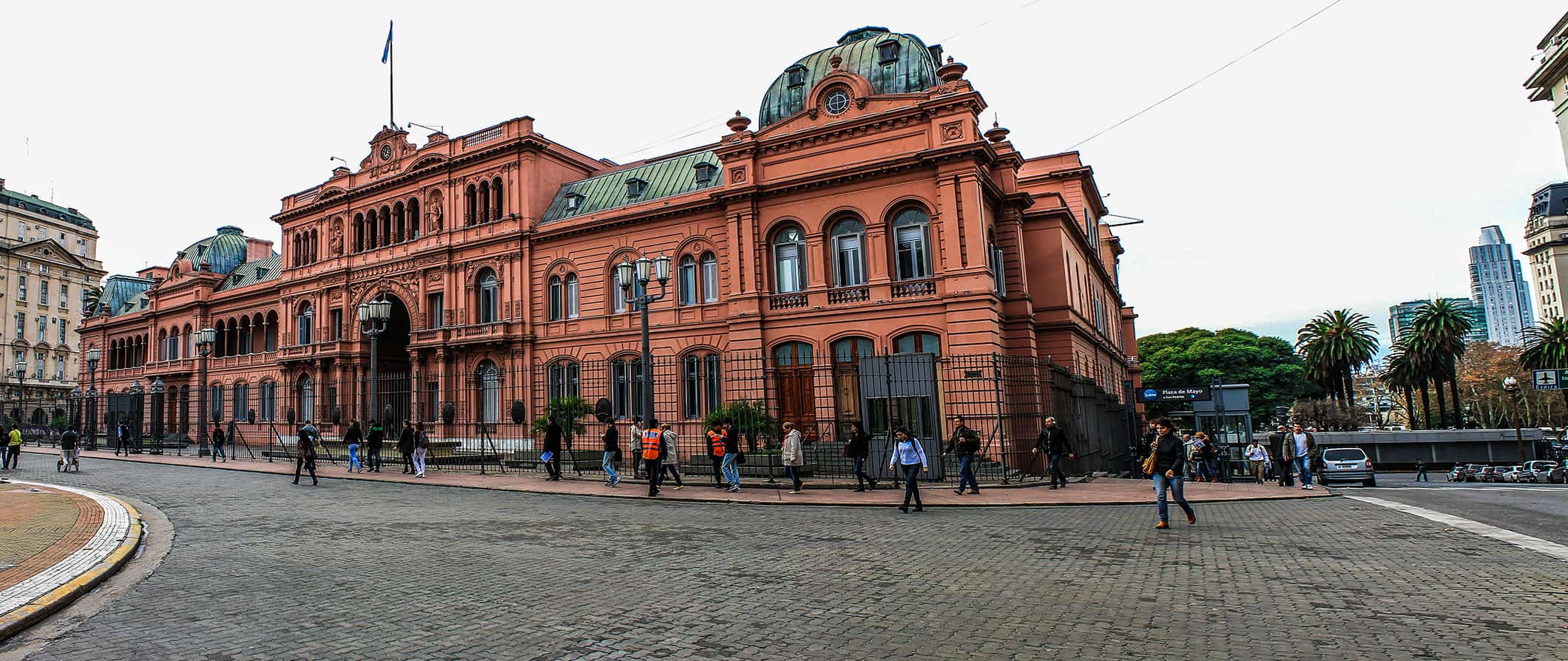 Street view in Buenos Aires, Argentina featuring people walking around in front of the historic Casa Rosada building