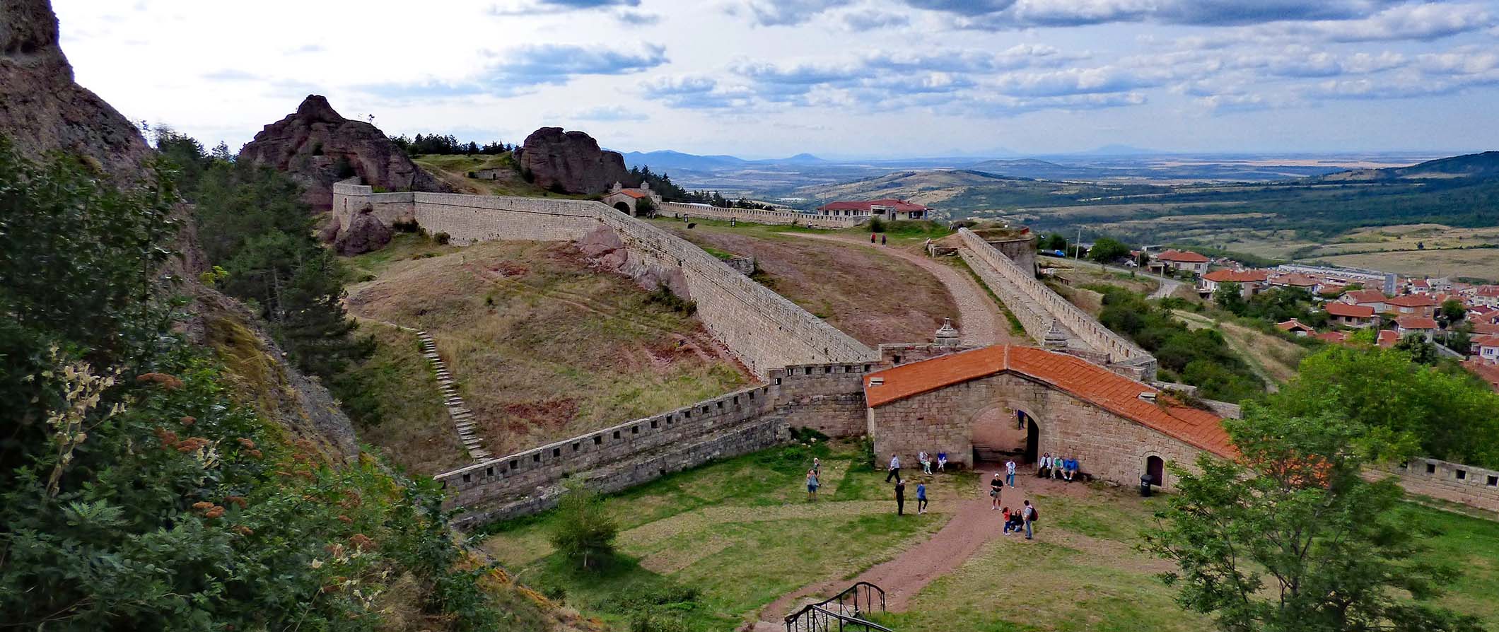 Historic walled fortress set against an expansive landscape of rolling hills in Bulgaria