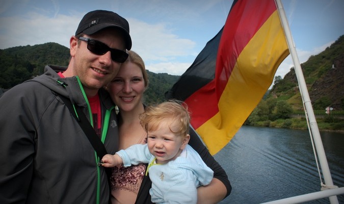 Traveling family of three posing with a German flag