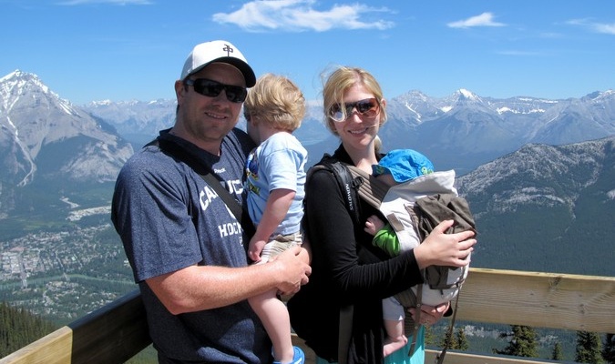 Traveling family of four in front of snow capped mountain range