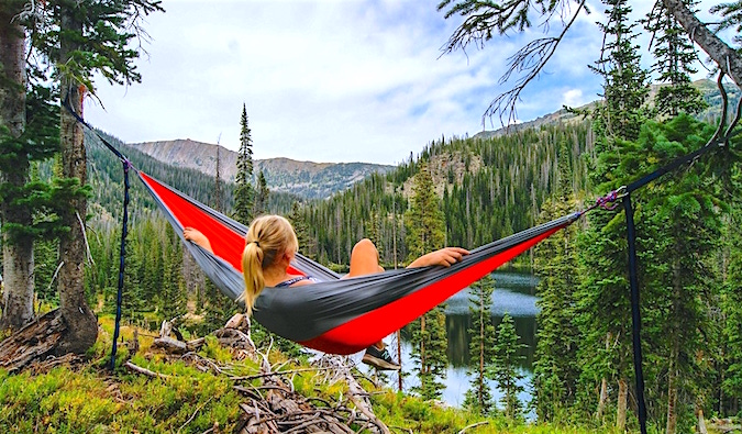 A solo female hiker relaxing in a colorful hammock in the forest