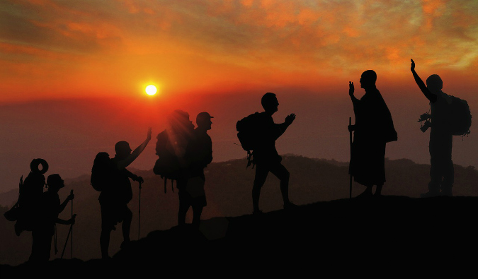 A group of travelers climbing a mountain during a bright sunset