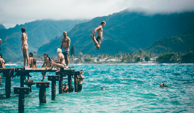 A group of travelers diving off a wharf on a sunny day