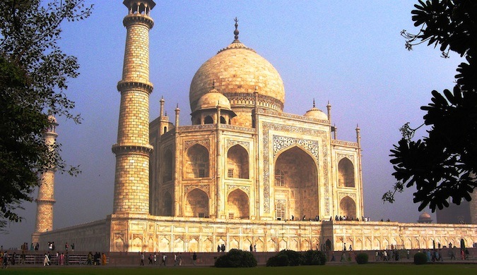 On a sunny day in India, the famous Taj Mahal is surrounded by tourists.