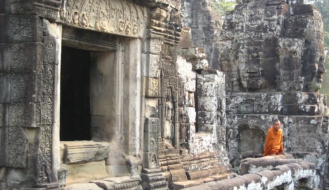 A dressed monk walks through one of the many ancient temples of Angkor Wat in Cambodia.