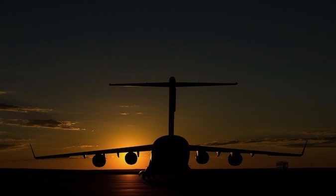 A dark and obscured plane at an airport during a bright sunset