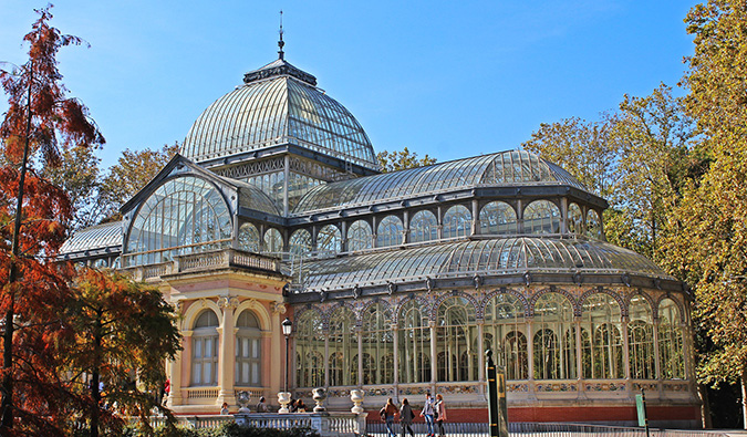 People standing outside the crystal palace and fountain in Retiro park, Madrid, Spain on a sunny day