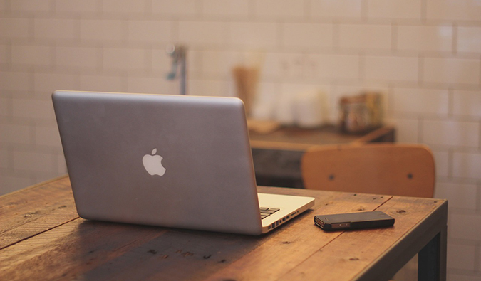 a laptop on a table beside a mobile phone