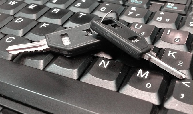 A pair of small keys resting on a computer laptop