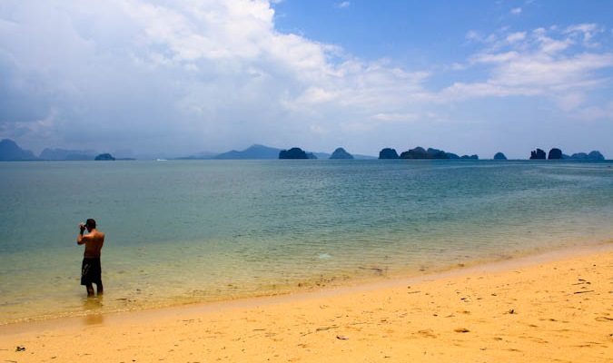 man on a beach in the water using a camera