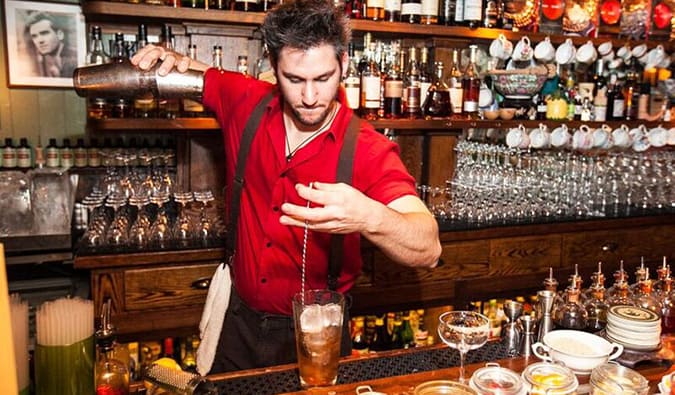 People drinking at a dimly lit prohibition bar called The Dead Rabbit