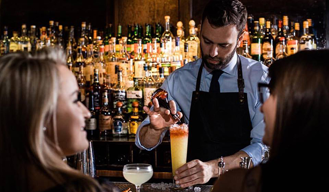 A bartender serves fancy cocktails to patrons at Death and Company in NYC