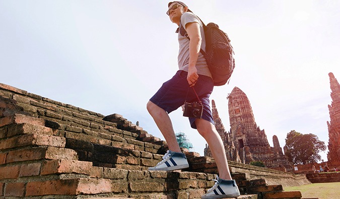 一位男性预算旅行者走在亚洲的一座古庙的步骤