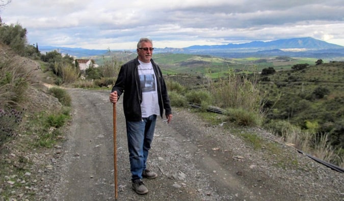 A retired traveler hiking on an empty road in Europe