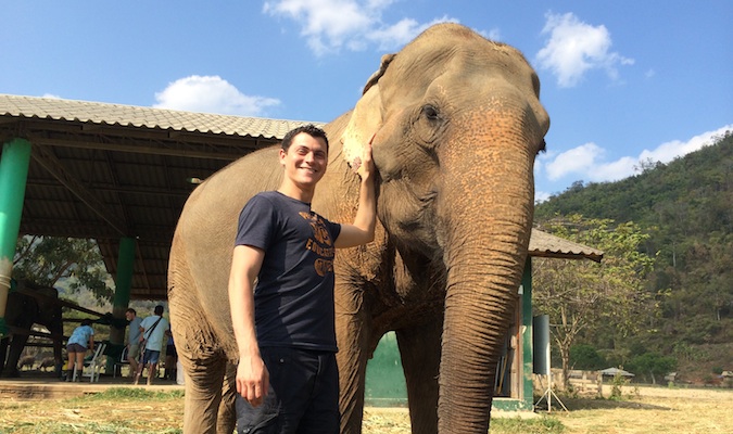 Nomadic Matt posing with an elephant at Elephant Nature Park in Thailand
