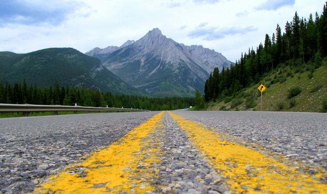 Yellow road lines going in the direction of a distant mountain