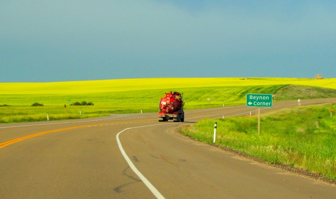 Red truck on an open road with a green field in the countryside