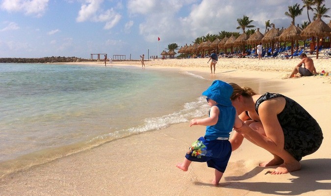 A father playing with his toddler in the water at the beach