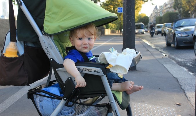 A cute baby smiling at camera in stroller while traveling abroad