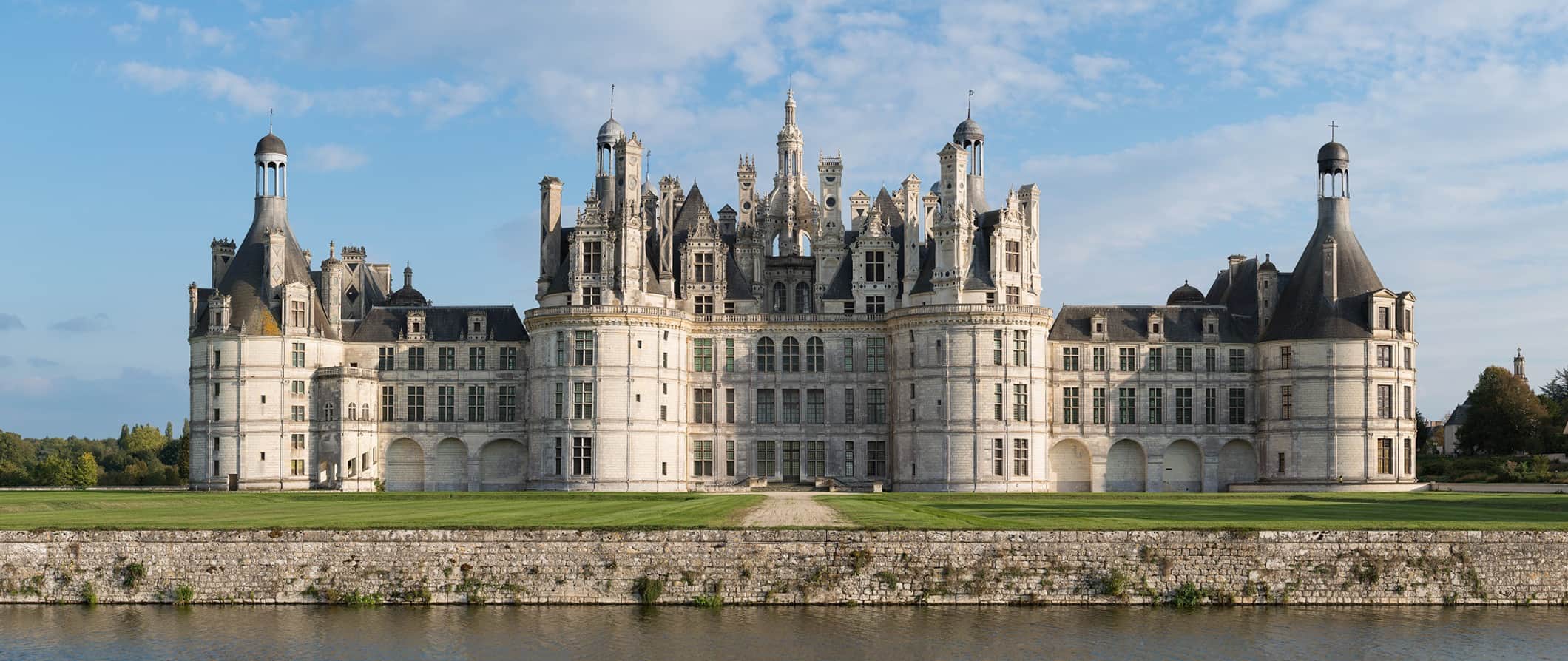 A huge historic French castle in the Loire Valley surrounded by grass and greenery