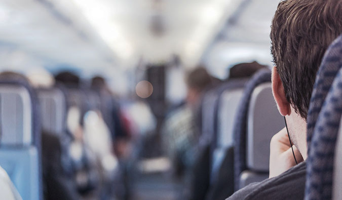 A man sitting in an airplane looking down the aisle at the flight attendant