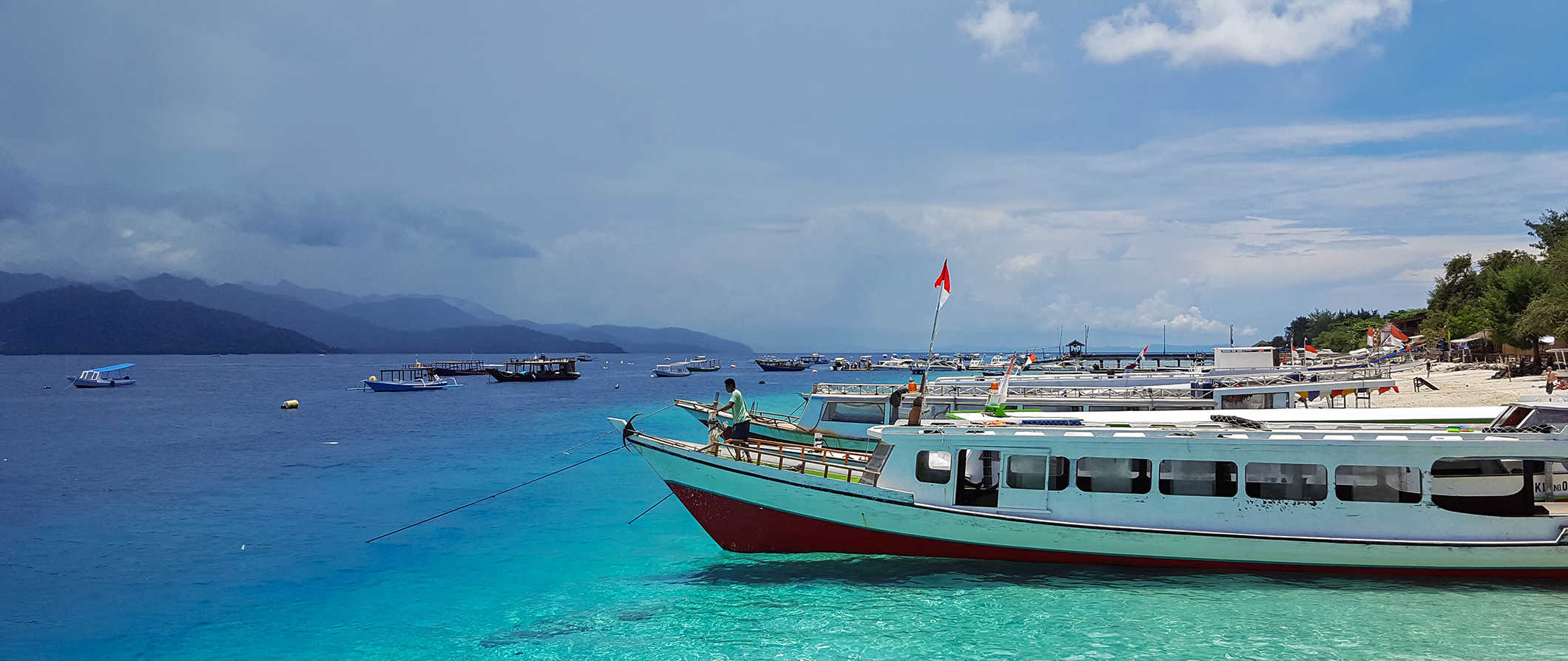 a gorgeous beach with a boat parked along the shore in the Gili Islands, Indonesia