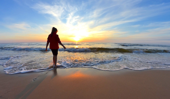 A lone woman walking barefoot on a picturesque beach