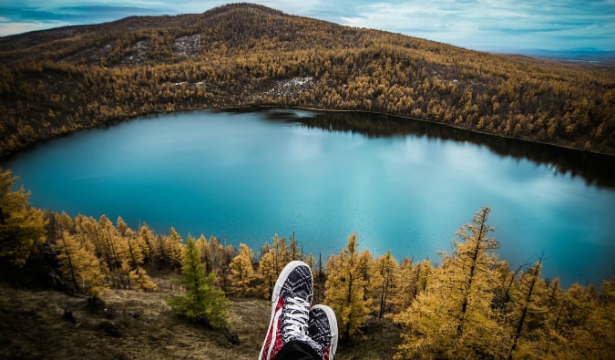 坐在山的山上的旅客俯视湖