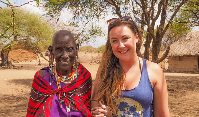 A solo female traveler posing with a local while volunteering in Africa