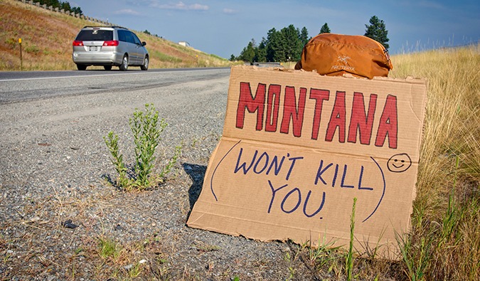 Hitchhiknig sign saying that Montana Won't Kill You