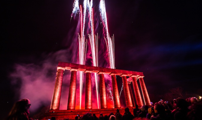 Red fireworks tower over Calton Hill during Hogmany in Scotland
