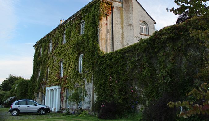 A beautiful vine-covered manor with a car in front at a house sit in Scotland