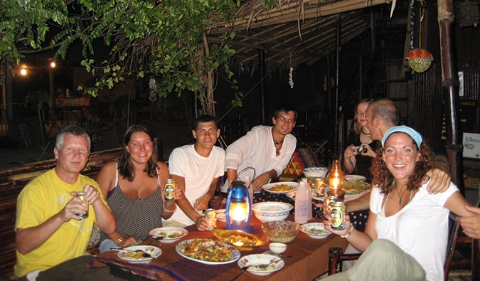 Eating dinner around a candlelit table with travelers outside in Thailand