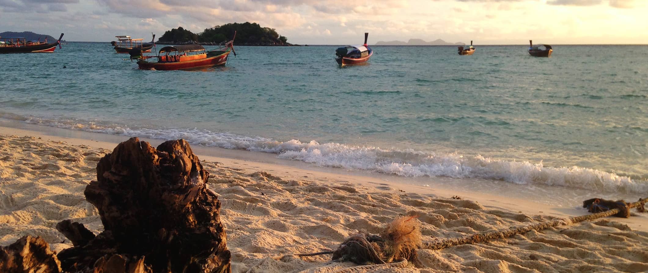 An empty beach in Ko Lipe, Thailand with small boats anchored out offshore