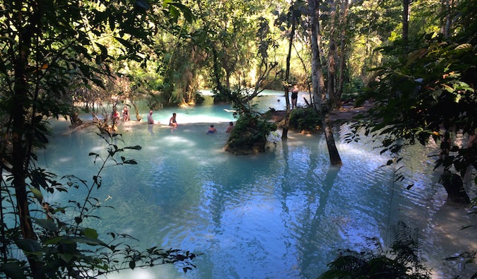 Travelers swimming in the Kuang Si waterfalls in Laos