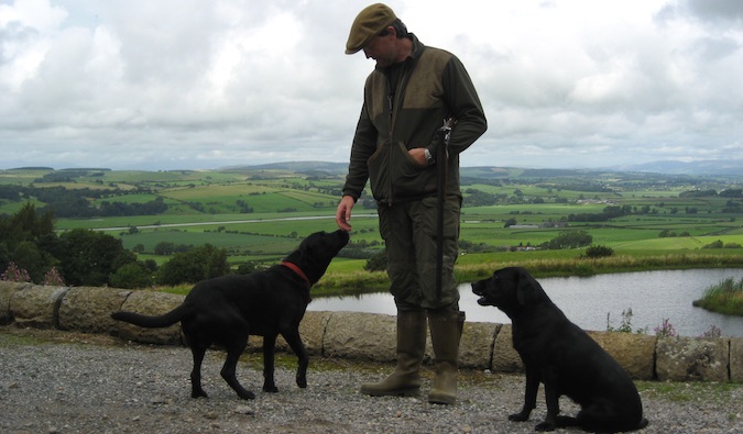 A British man with two dogs in from of the Lake in England
