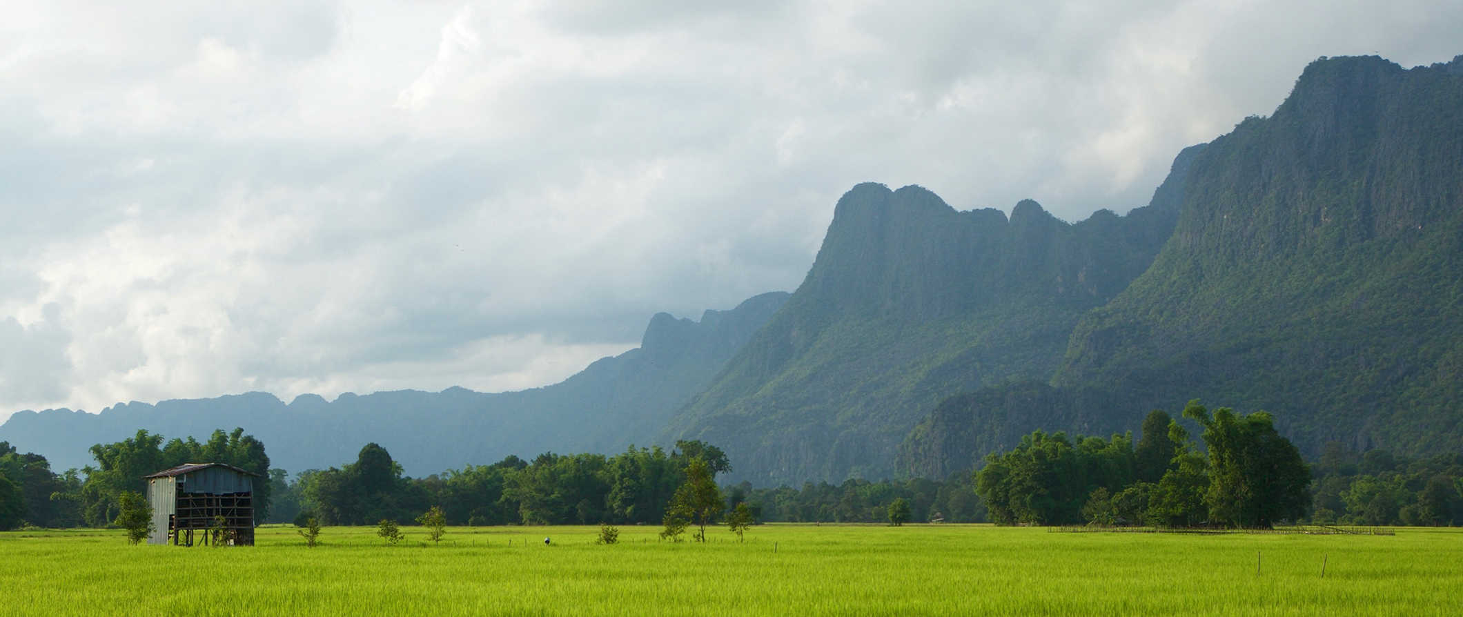 The lush hills and mountains of beautiful Laos, with a green field in the foreground