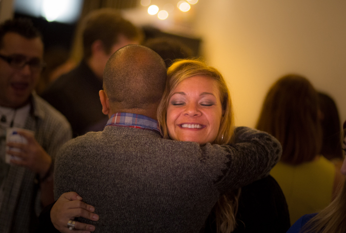 Candid travel picture of two people hugging at a party