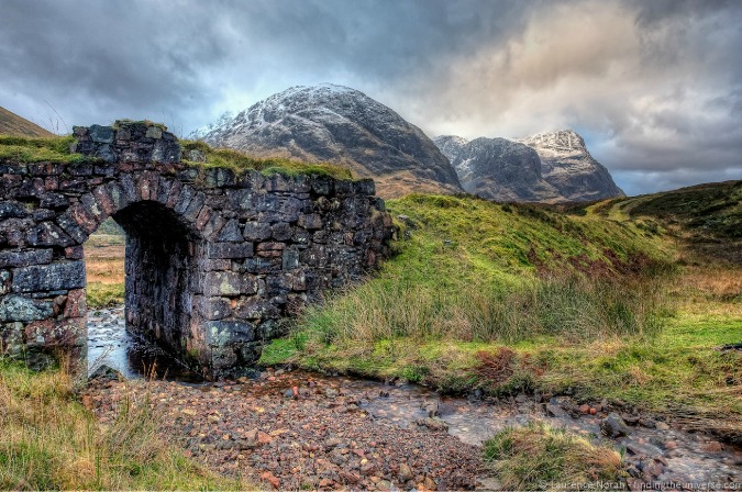 Captivating photograph of a stone wall door and mountain range in rainy Europe