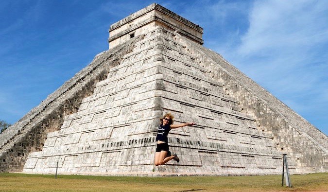 A woman visiting Chichen Itza, Mexico leaping in the air for a photo