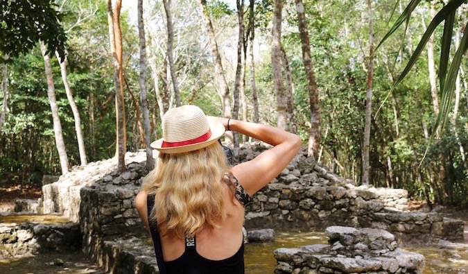 A solo female traveler taking a photo in the forest