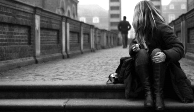 A black and white photo of a solo female traveler sitting on some stairs